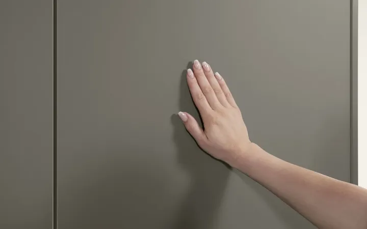 Frauenhand ertastet Küchenfront in taupegrau